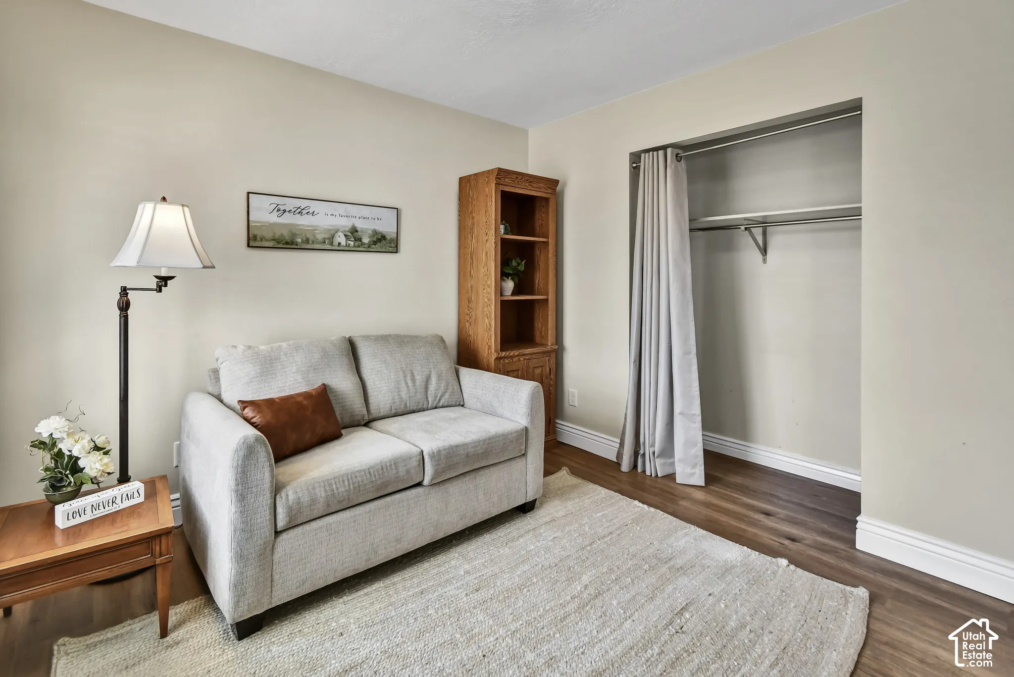 Wood-finish flooring, light neutral wall paint, and a built-in closet with shelving and a curtain