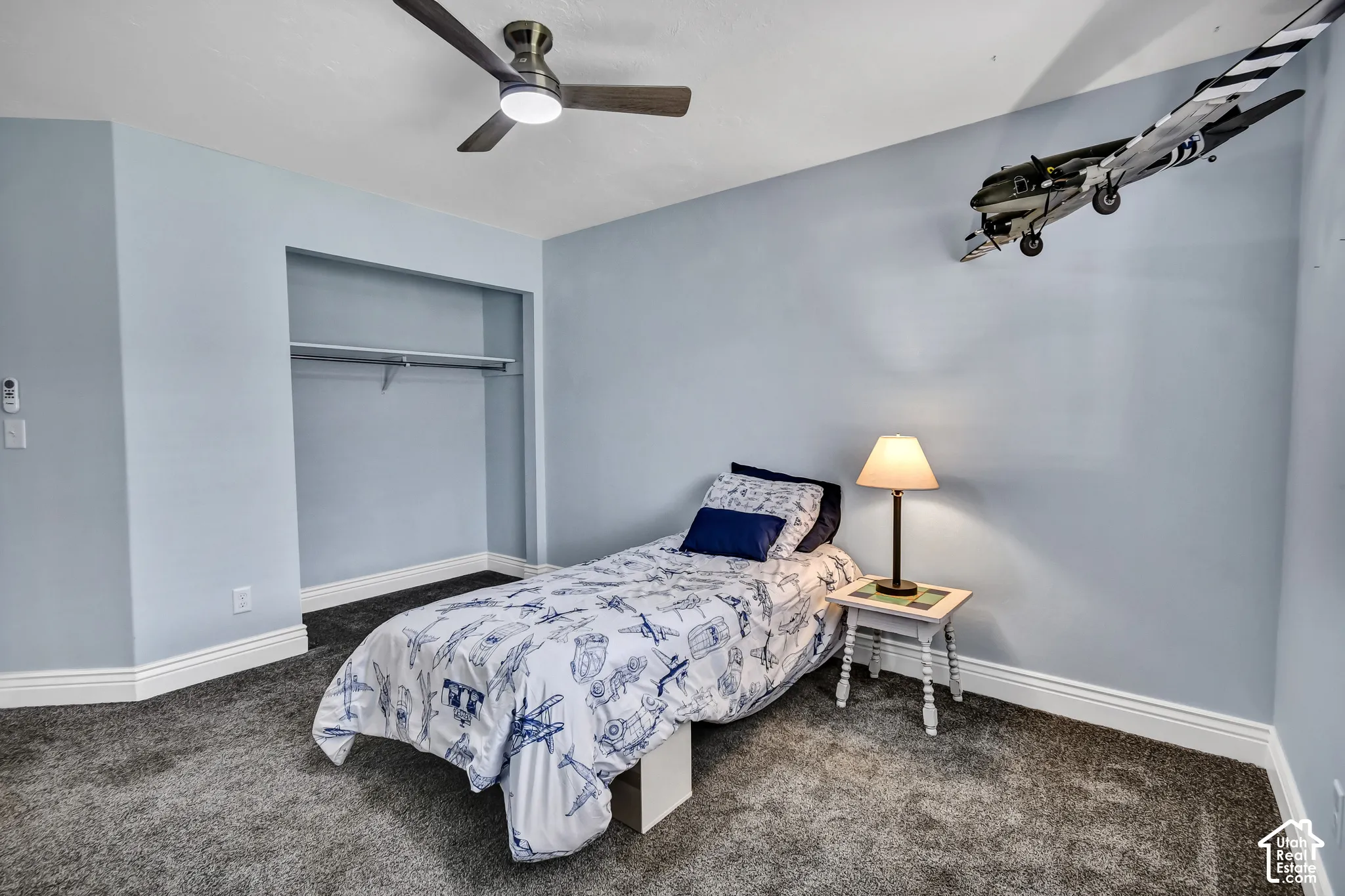 Recessed closet space with a clothing rod, ceiling fan with integrated lighting, and plush carpeting