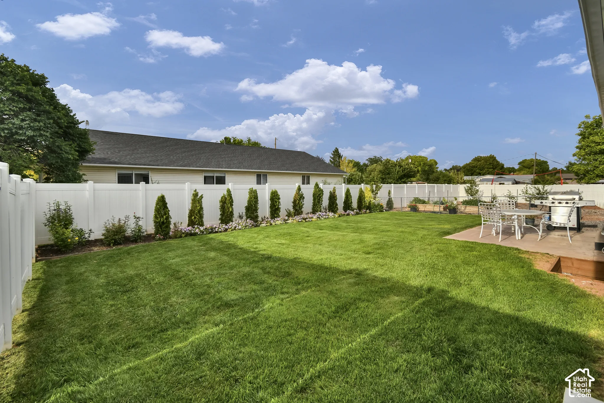 Expansive lawn area, white privacy fencing, and a paved patio