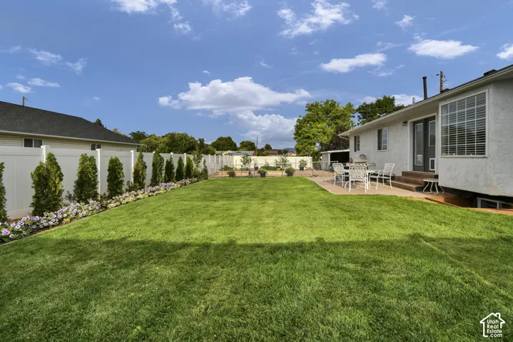 Expansive backyard with a manicured lawn, a large concrete patio, and a privacy fence
