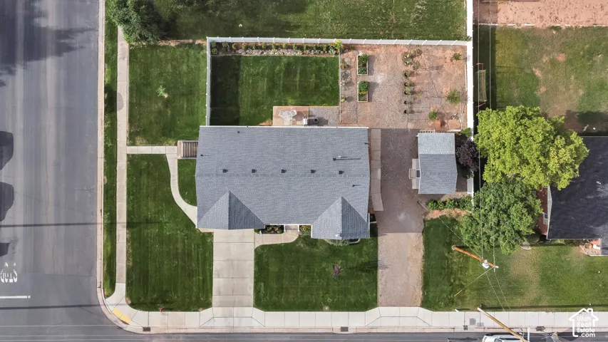 Gable roofline, front lawn with concrete walkway and driveway, gravel side yard, fenced backyard with lawn, and an outbuilding with a gable roof