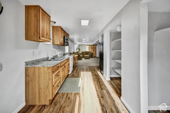 Wood-finish flooring throughout, wood cabinetry, granite-style countertops, white kitchen appliances, and built-in shelving