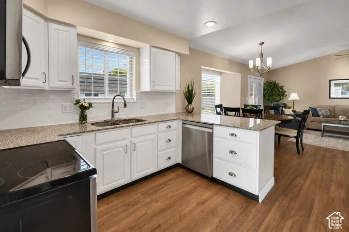 White cabinetry with dark hardware, a double basin sink, and stainless steel appliances