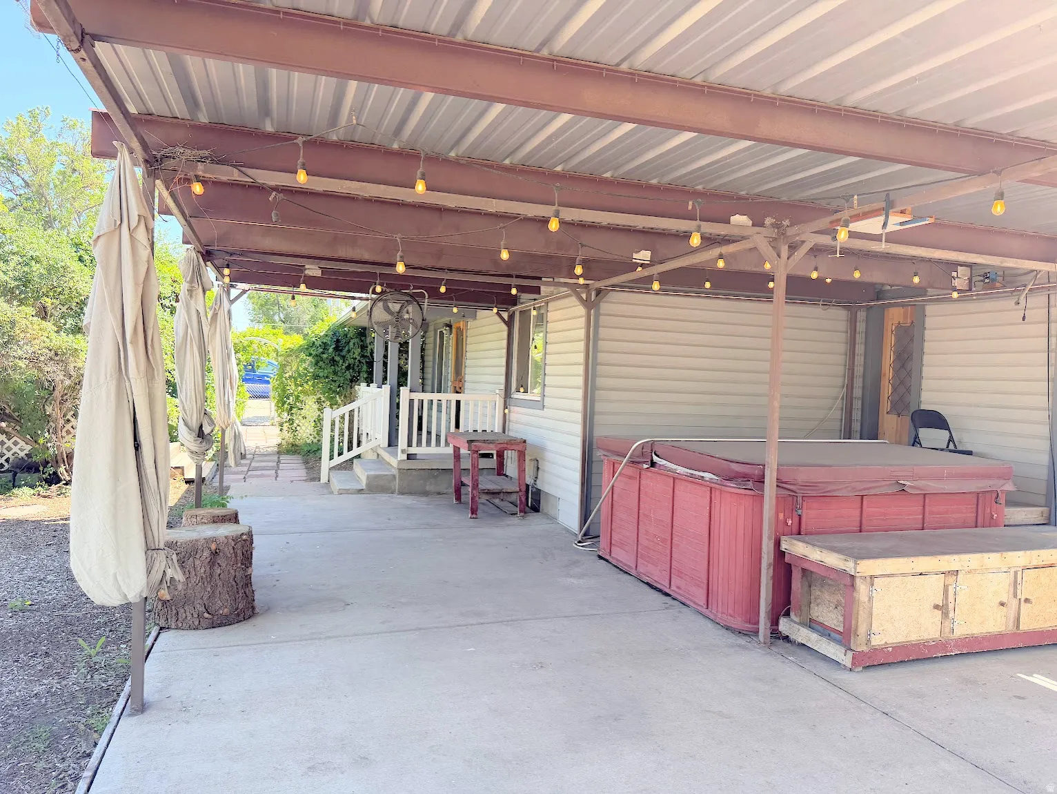 Covered patio with string lighting, concrete flooring, and a hot tub