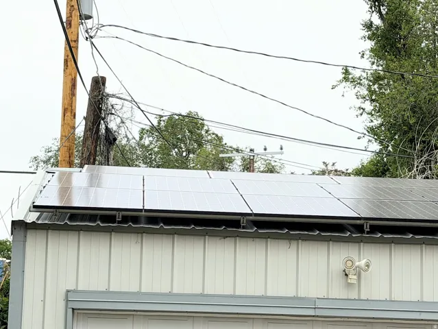 Rooftop solar panel array on a white corrugated metal building with a security light fixture