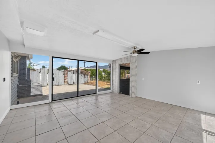 Tile flooring, sliding glass door, exposed brick accent wall, ceiling fan, and recessed lighting