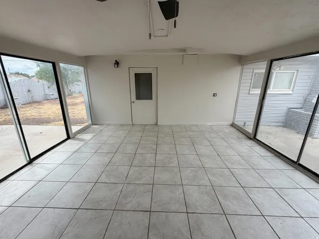 Tile flooring, expansive glass panels, white interior walls, exterior door with frosted glass, wall-mounted light fixture