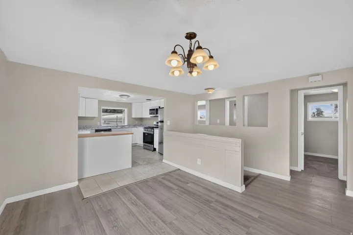 Wood-finish flooring, recessed lighting, and a transitional chandelier