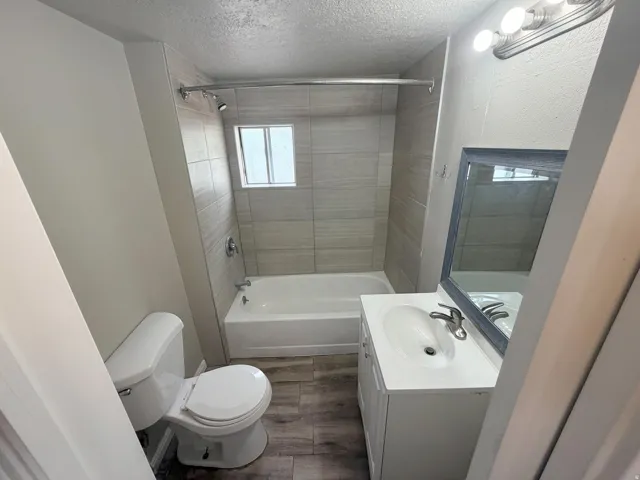 Full bathroom featuring a white vanity with integrated sink, a framed mirror, and a shower/tub combination with tiled surround