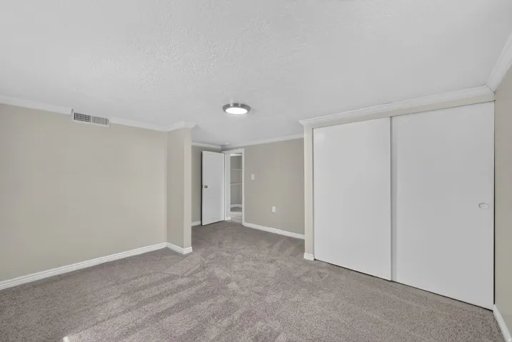 Wall-to-wall carpeting, crown molding, and a flush-mount ceiling light