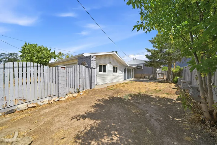 Expansive backyard space with perimeter fencing, mature trees, and a siding exterior