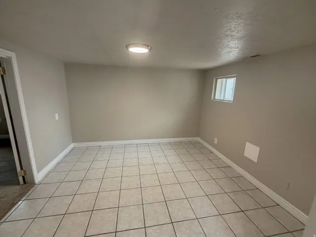 Rectangular room featuring neutral wall paint, tiled flooring, and a flush-mount ceiling light