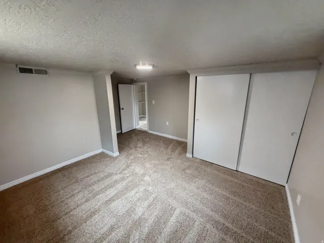 Neutral wall color, wall-to-wall carpeting, recessed ceiling lighting, built-in closet with sliding doors, and a paneled interior door