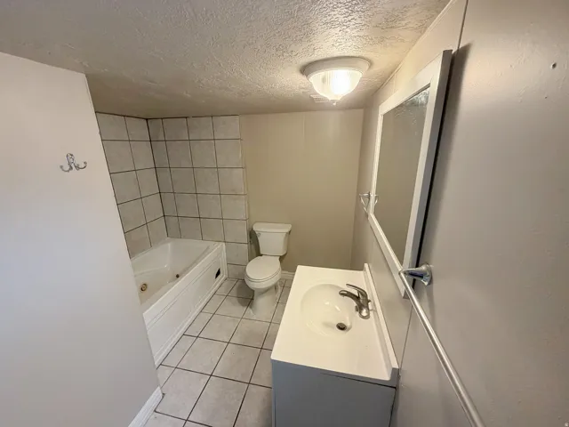 Bathroom featuring a built-in tub, tiled shower surround, a vanity with an integrated sink, and a framed wall mirror