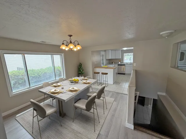 Dining area featuring a contemporary chandelier, large window, and wood-finish flooring