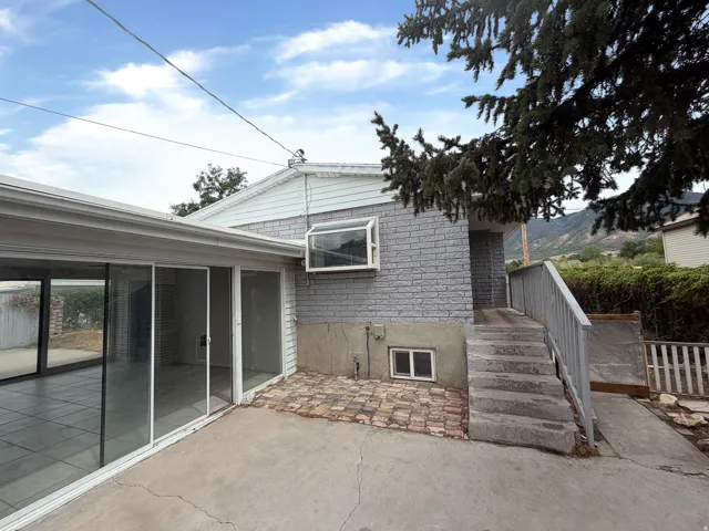 Sliding glass doors, concrete patio, brick accent paving, brick exterior, and a secondary window
