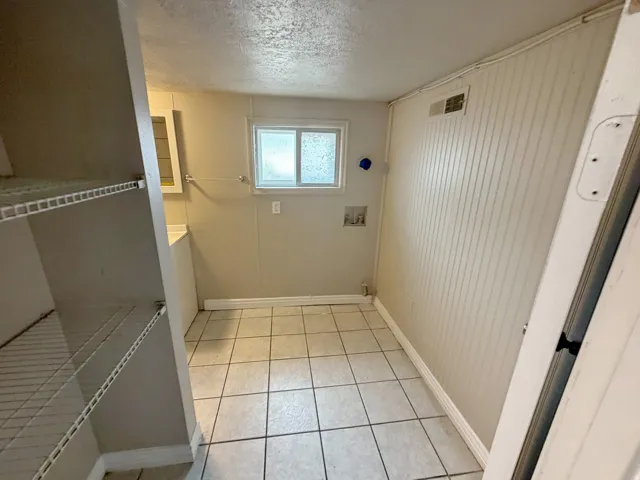 Utility area featuring ceramic tile flooring, beadboard wall paneling, a single window, and wire shelving