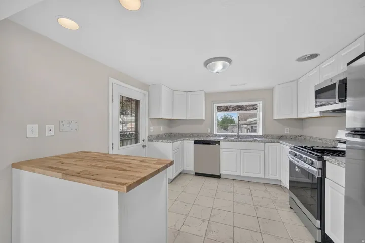 Kitchen featuring white cabinetry, light-toned countertops, stainless steel appliances, and tile flooring