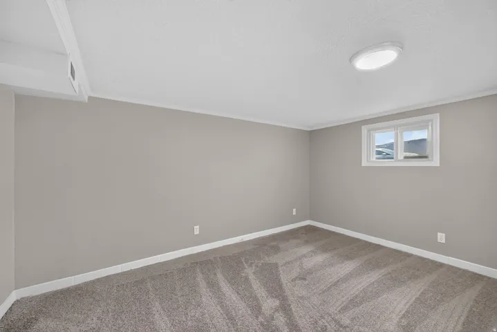 Neutral tone wall finish, window with white trim, recessed ceiling light, and carpeted flooring