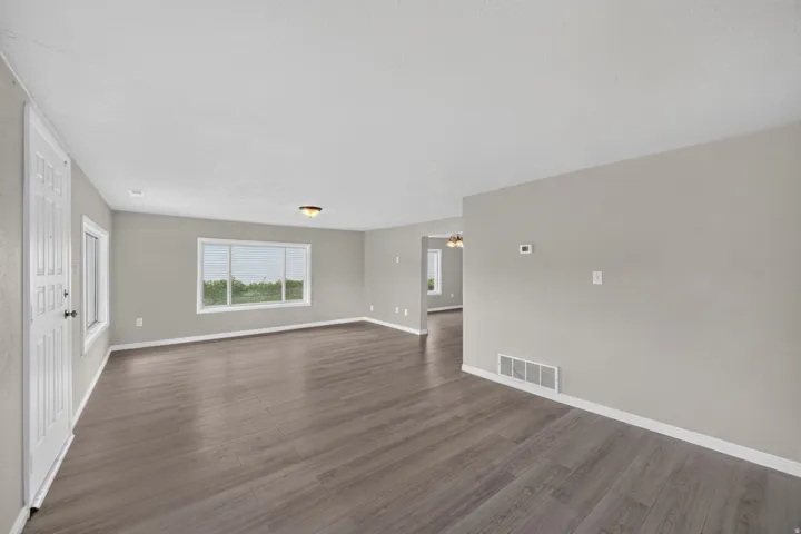 Spacious room featuring wood-finish flooring, light gray walls, and white trim