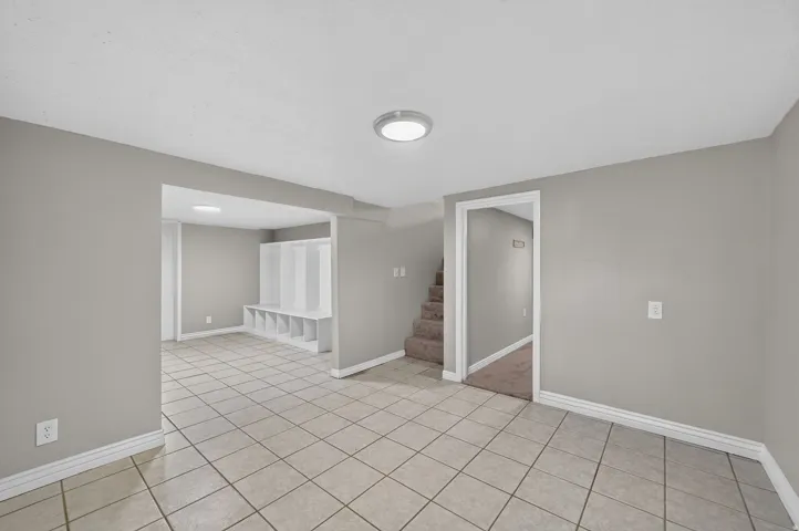 Spacious room featuring tile flooring, neutral wall tones, recessed lighting, and a built-in storage bench with cubbies