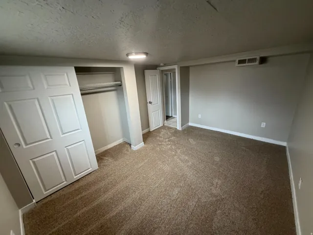 Neutral-toned wall paint, textured ceiling finish, recessed light fixture, carpet flooring, bi-fold closet doors, and interior paneled door