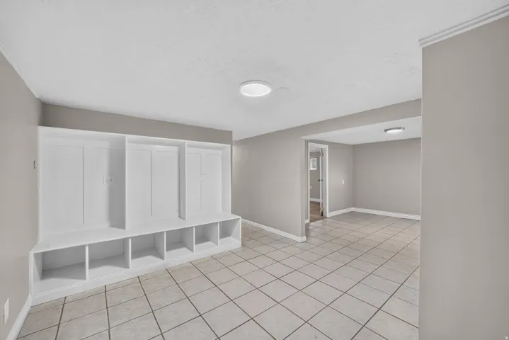 Built-in storage bench with cubbies, white tile flooring, and neutral wall paint