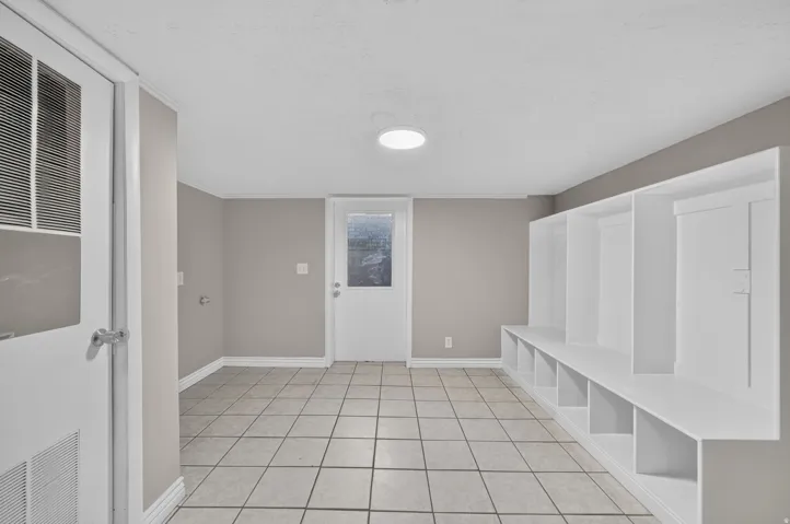 Tiled flooring with a neutral finish, built-in storage cubbies, recessed ceiling light fixture, and a white paneled door