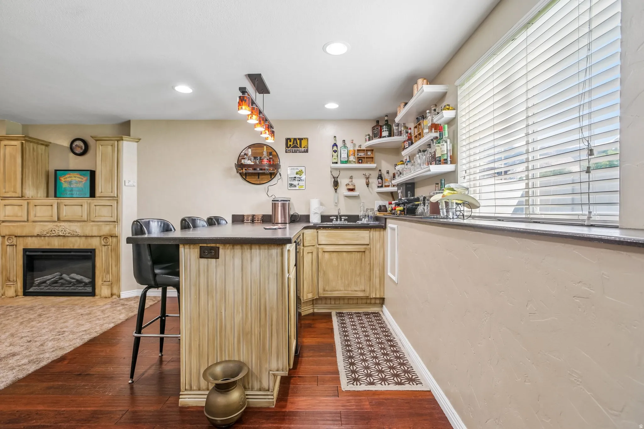 Wet bar with built-in cabinetry, dark countertops, a sink, and pendant lighting