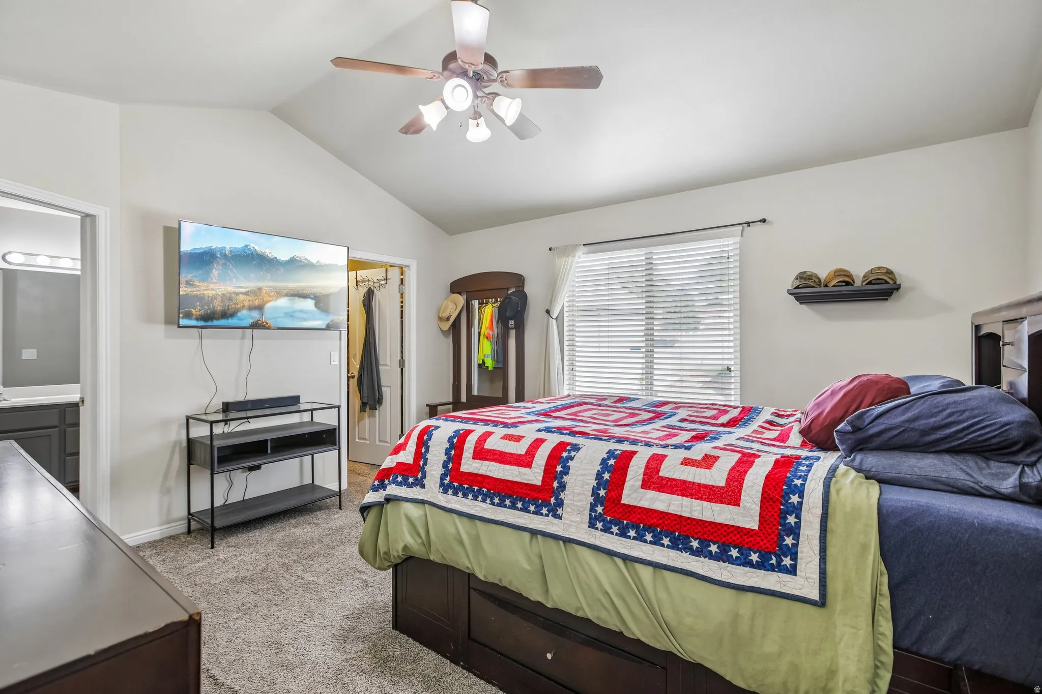 Vaulted ceiling with a ceiling fan, carpeted flooring, and window with blinds