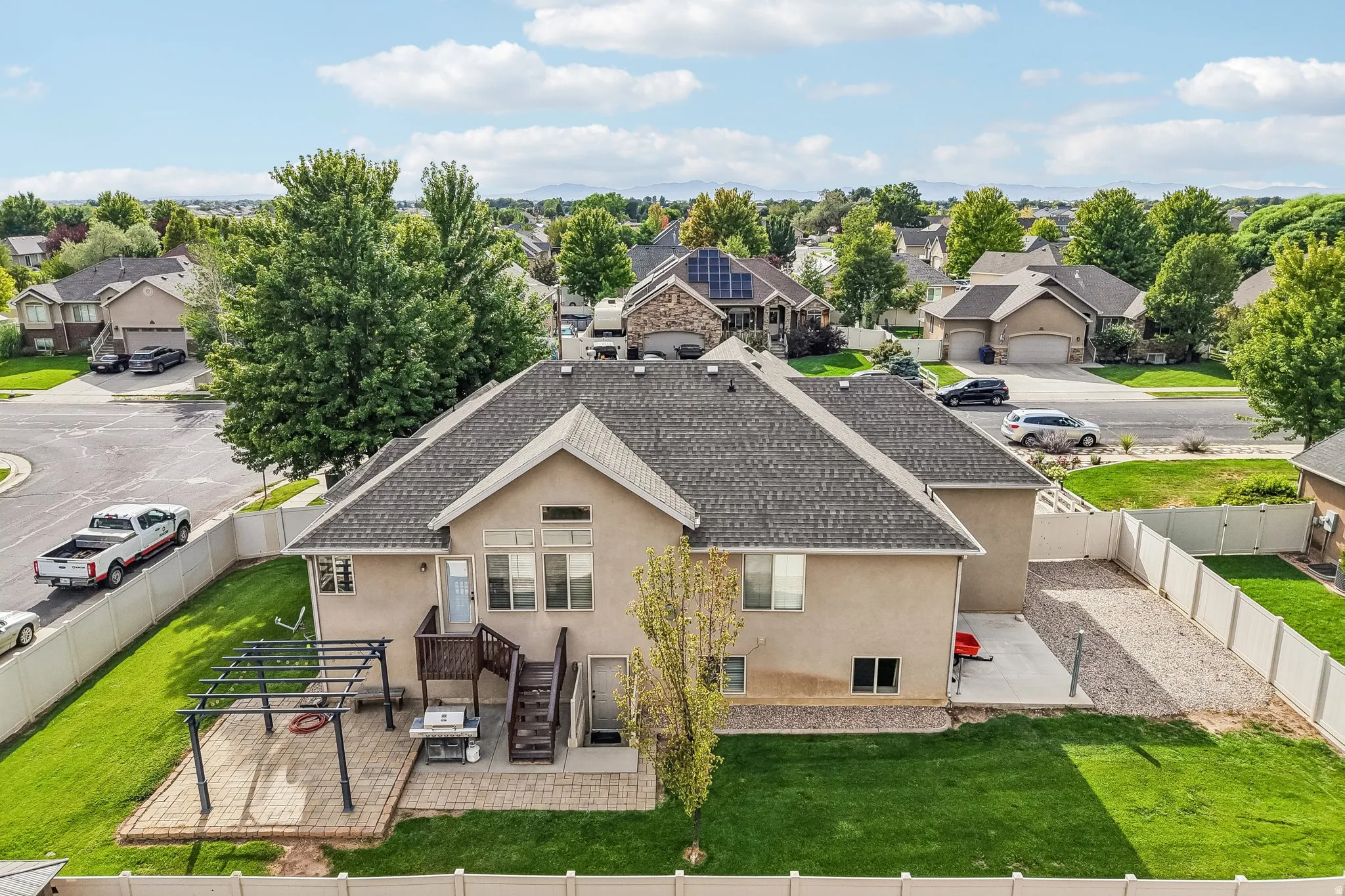 Expansive backyard featuring a manicured lawn, brick paver patio, and multi-level wooden deck