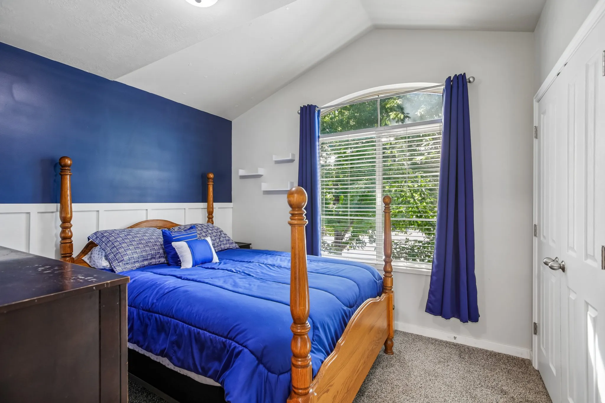 Vaulted ceiling with an arched window, white board and batten paneling, and a panel door with a silver-tone handle