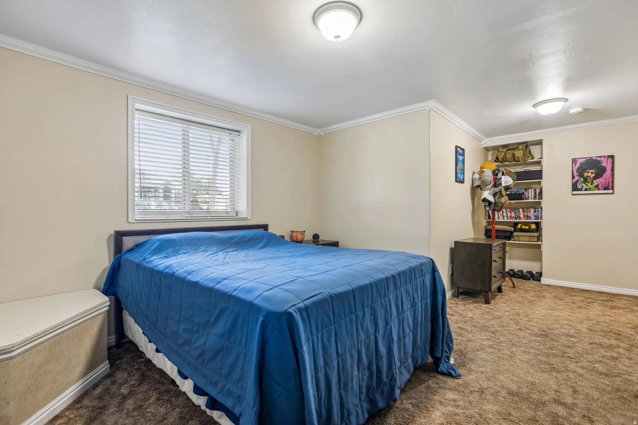 Recessed window with blinds, built-in shelving, and neutral wall color with crown molding