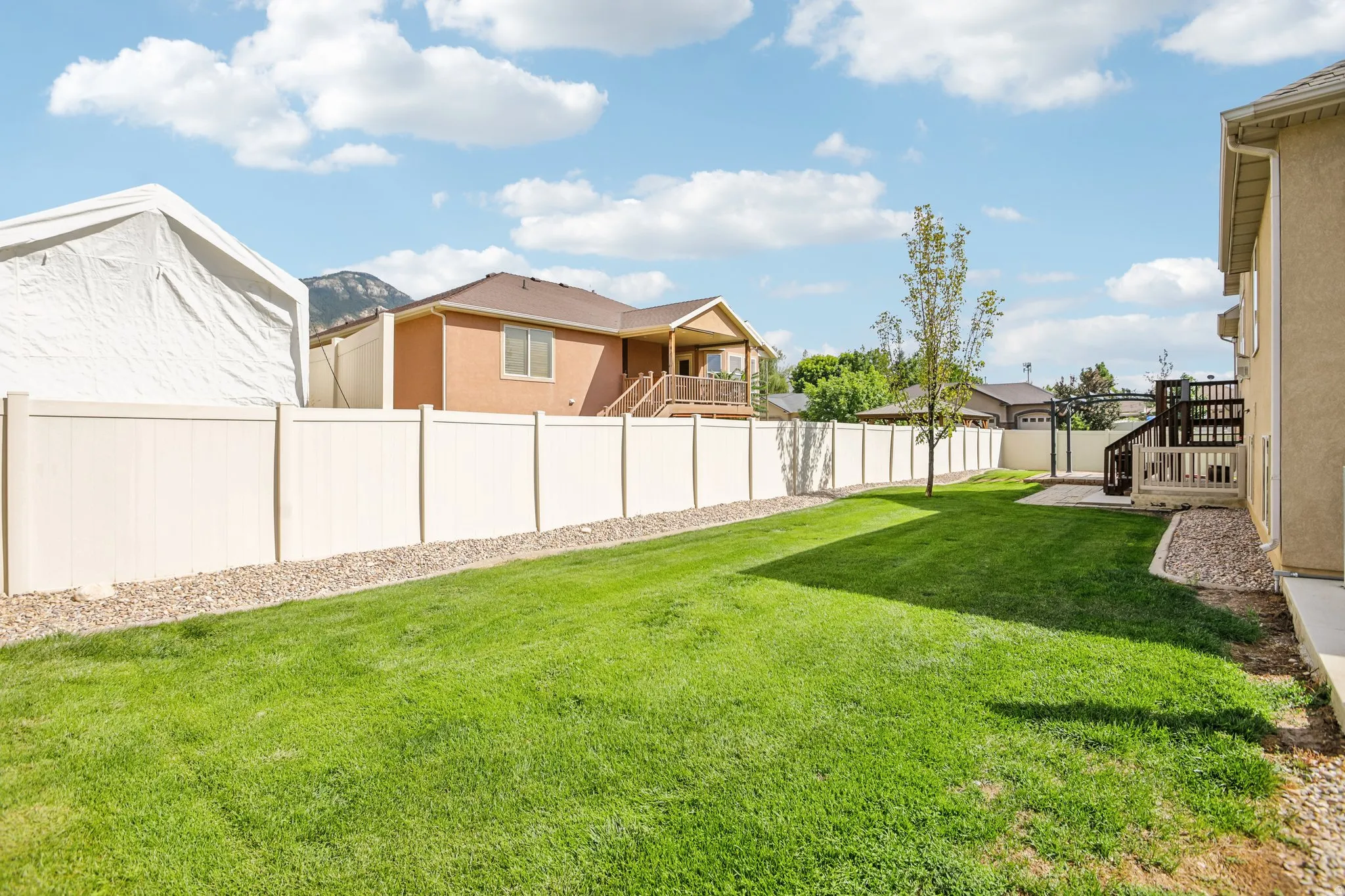 Expansive grassy yard with a light-toned privacy fence and a dedicated patio area