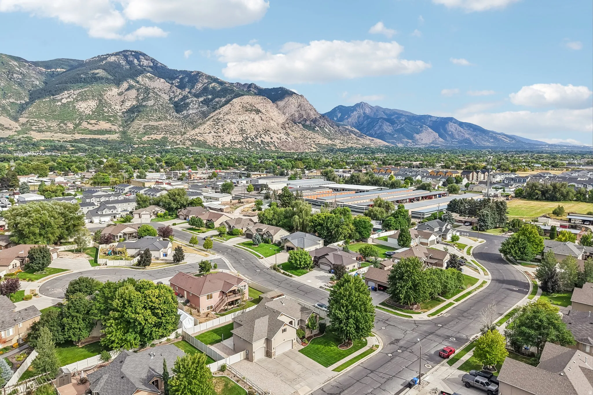Residential neighborhood with established homes, mature trees, and mountainous backdrop