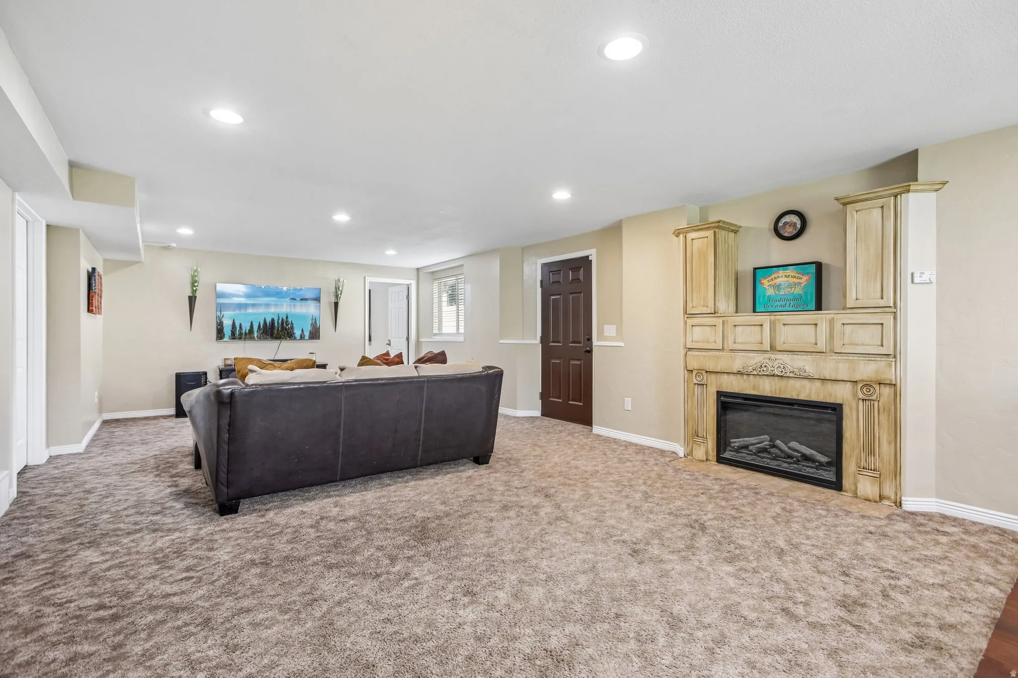 Spacious recreation room featuring recessed lighting, plush carpeting, a built-in fireplace with an ornate mantel, and a solid panel door