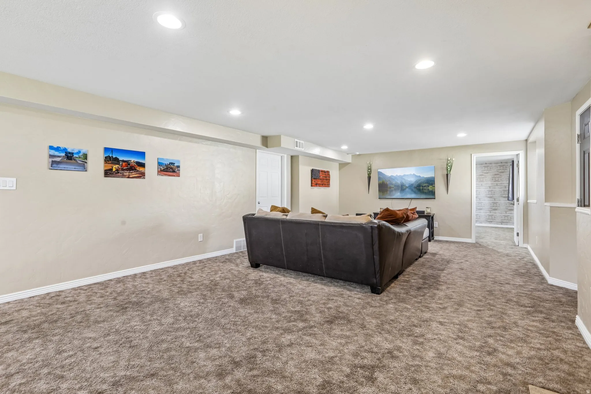 Recessed lighting illuminates the space, featuring textured walls and soft carpeting