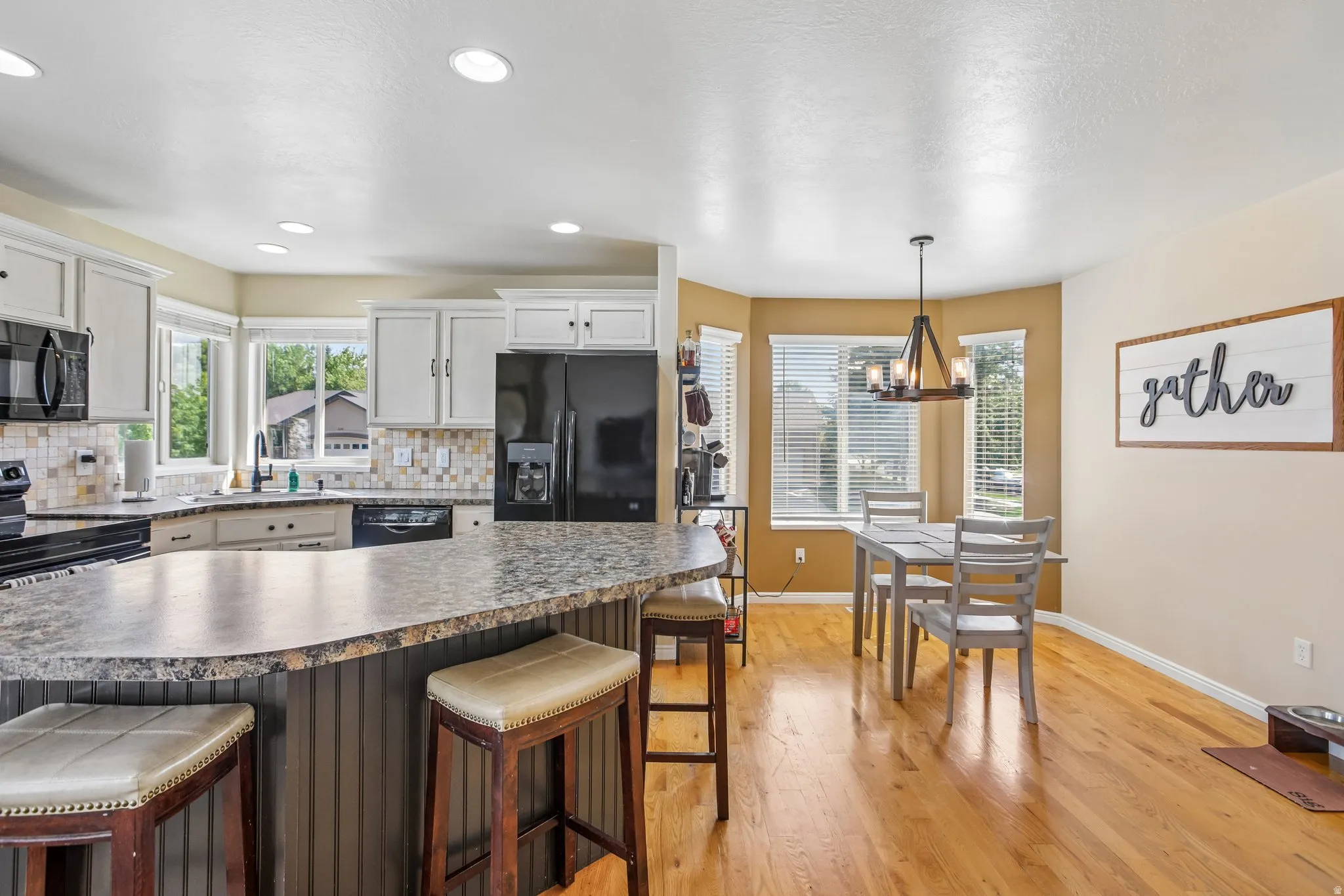 Open-concept kitchen with recessed lighting, light-toned cabinetry, and a curved island featuring a built-in breakfast bar