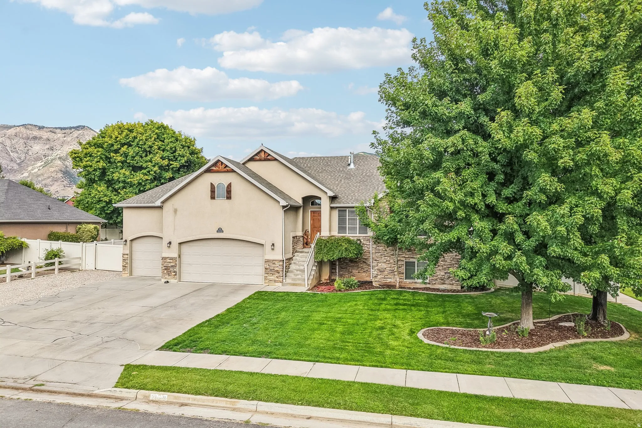 Stucco exterior with stone accents, attached multi-car garages, and a paved driveway