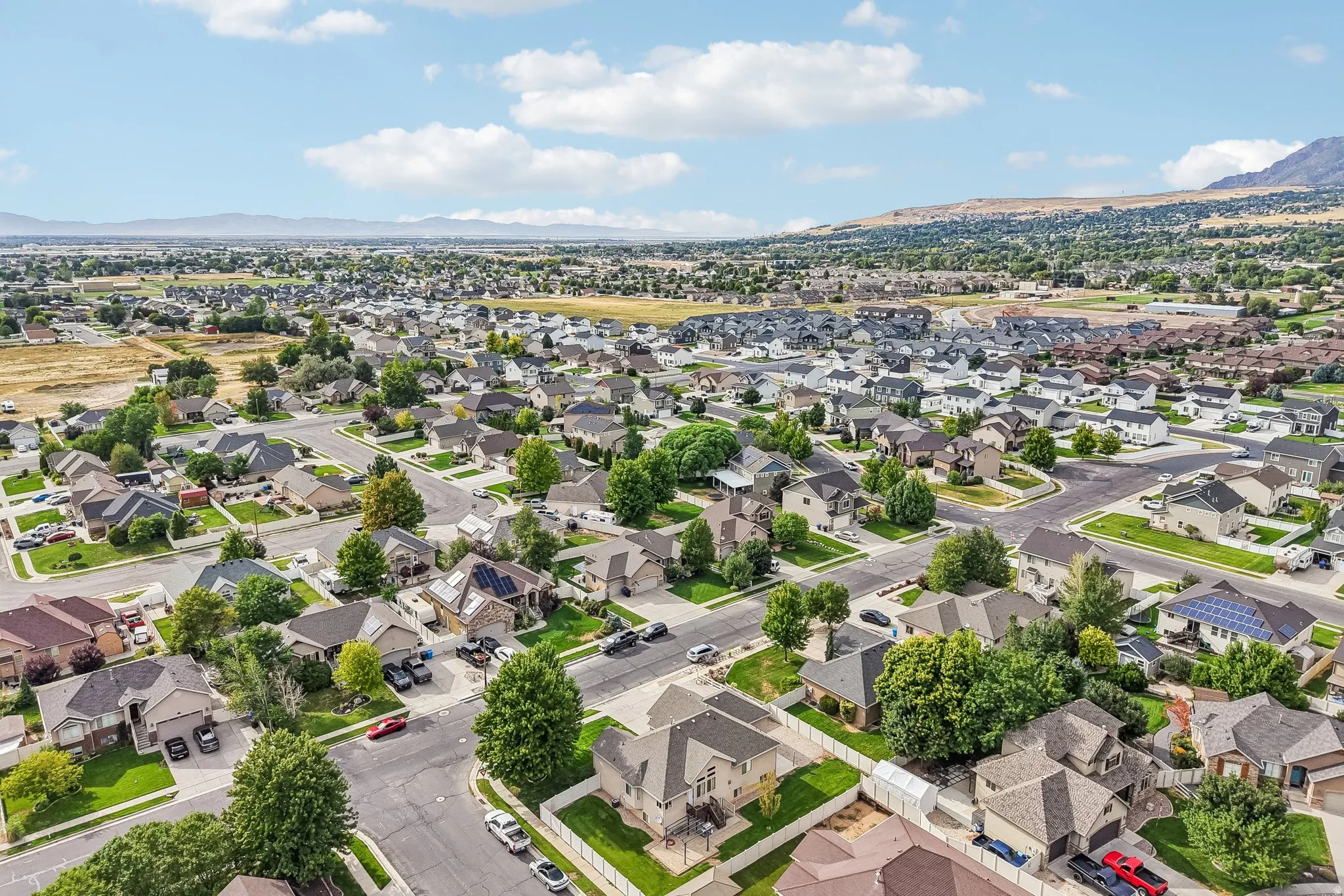 Residential neighborhood with mature trees, paved streets, and a mountain backdrop