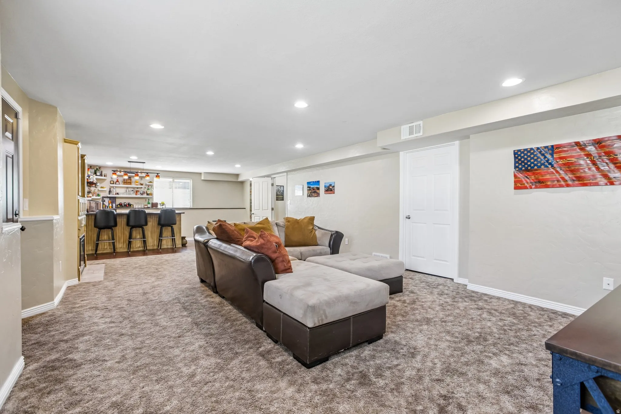 Carpeted lounge area with recessed lighting, built-in wet bar, and paneled doors