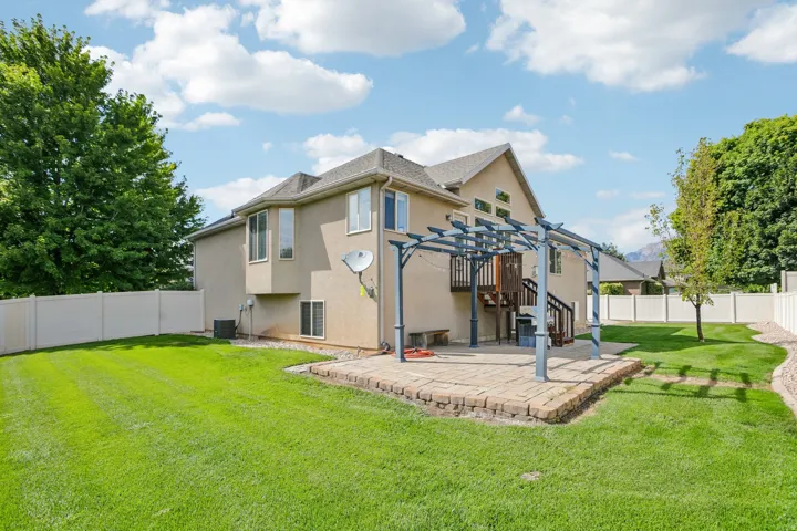 Expansive backyard featuring a manicured lawn, full privacy fencing, and a paver patio with a pergola