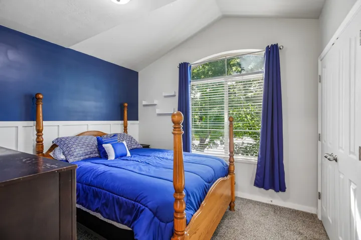 Vaulted ceiling with an arched window, white board and batten paneling, and a panel door with a silver-tone handle