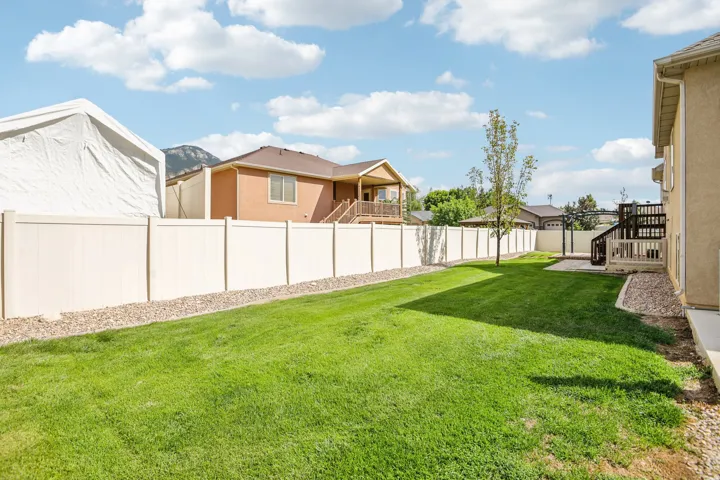 Expansive grassy yard with a light-toned privacy fence and a dedicated patio area