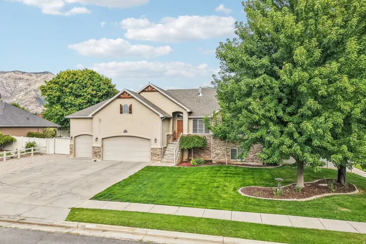 Stucco exterior with stone accents, attached multi-car garages, and a paved driveway