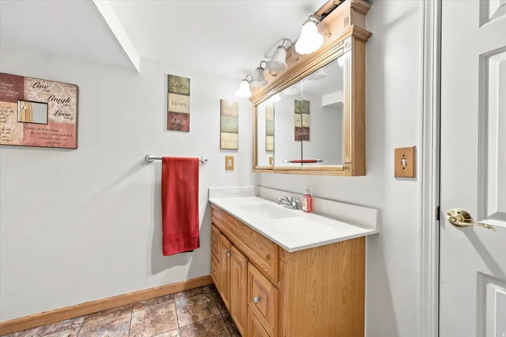 Double vanity with integrated sinks, wood-finish cabinetry, built-in medicine cabinet, and overhead vanity lighting