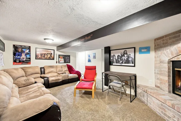 Recessed lighting, exposed structural beam, brick-faced fireplace, and carpeted flooring