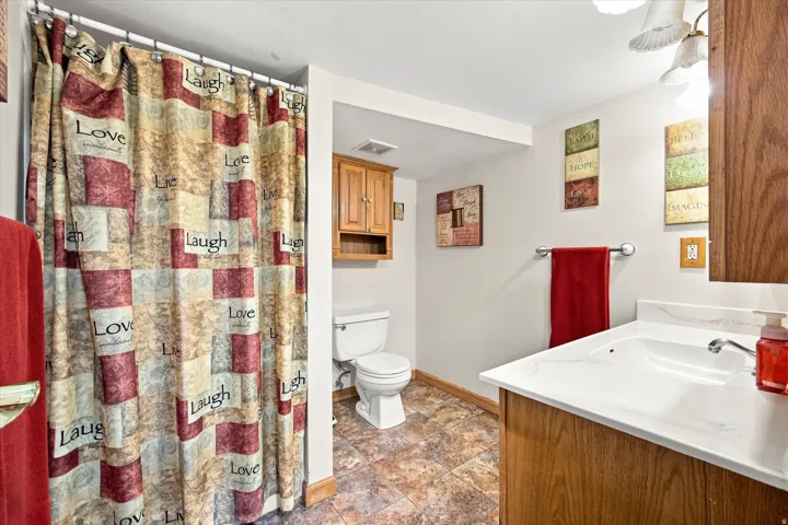 Vanity with integrated sink, wood-finish cabinetry, and overhead lighting