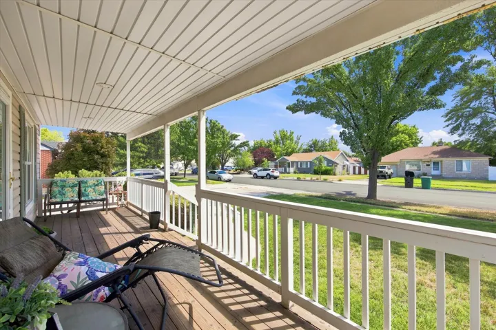 Covered porch with wood-finish flooring, white railing, and exterior siding