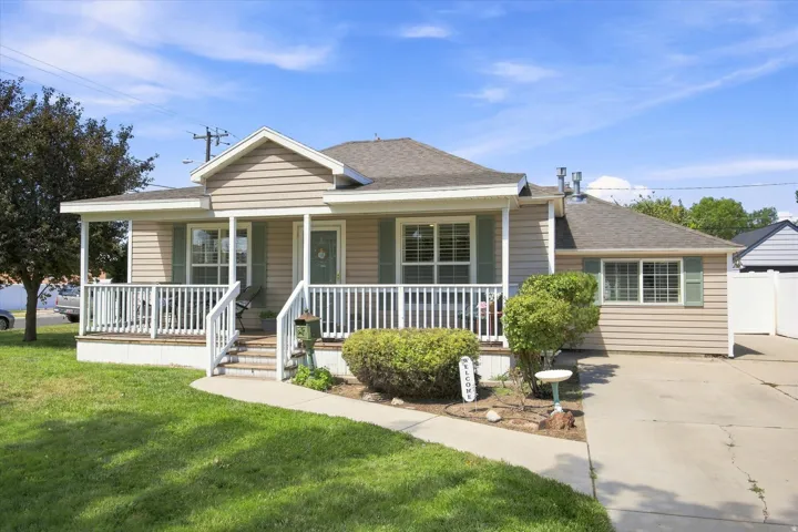 Siding exterior with a covered front porch, white railing, and exterior shutters